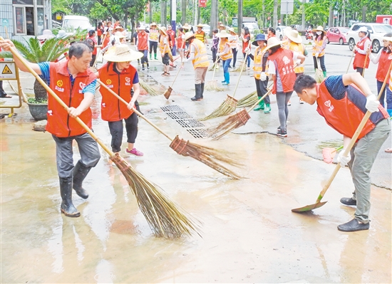 大雨过后，水浸过的路面积满黄泥和杂物，大批义工利用休息时间清理蓬江区建设路的淤泥与杂物。